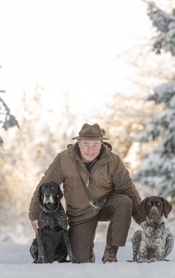 Herrchen mit Hunden auf dem Winterwanderweg im schneebedeckten Wald