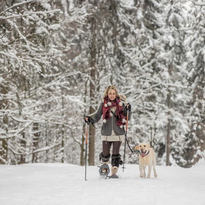 Dame beim Schneeschuhwandern mit Hund