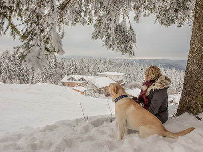 Hund und Frauchen schauen in der Winterlanschaft zum Hundehotel