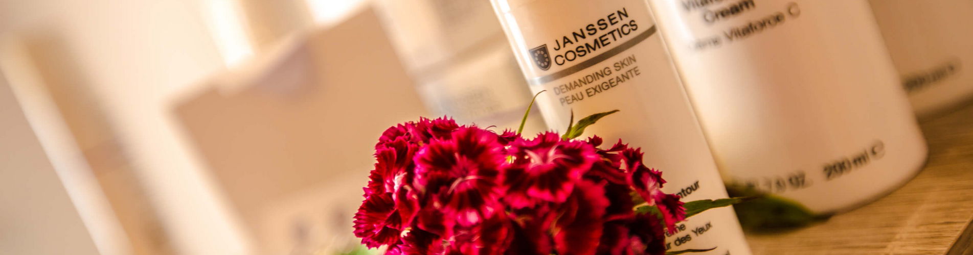 Nahaufnahmen mit Blume von den verschiedenenen Kosmetikutensilien der Firma Janssen Cosmetics