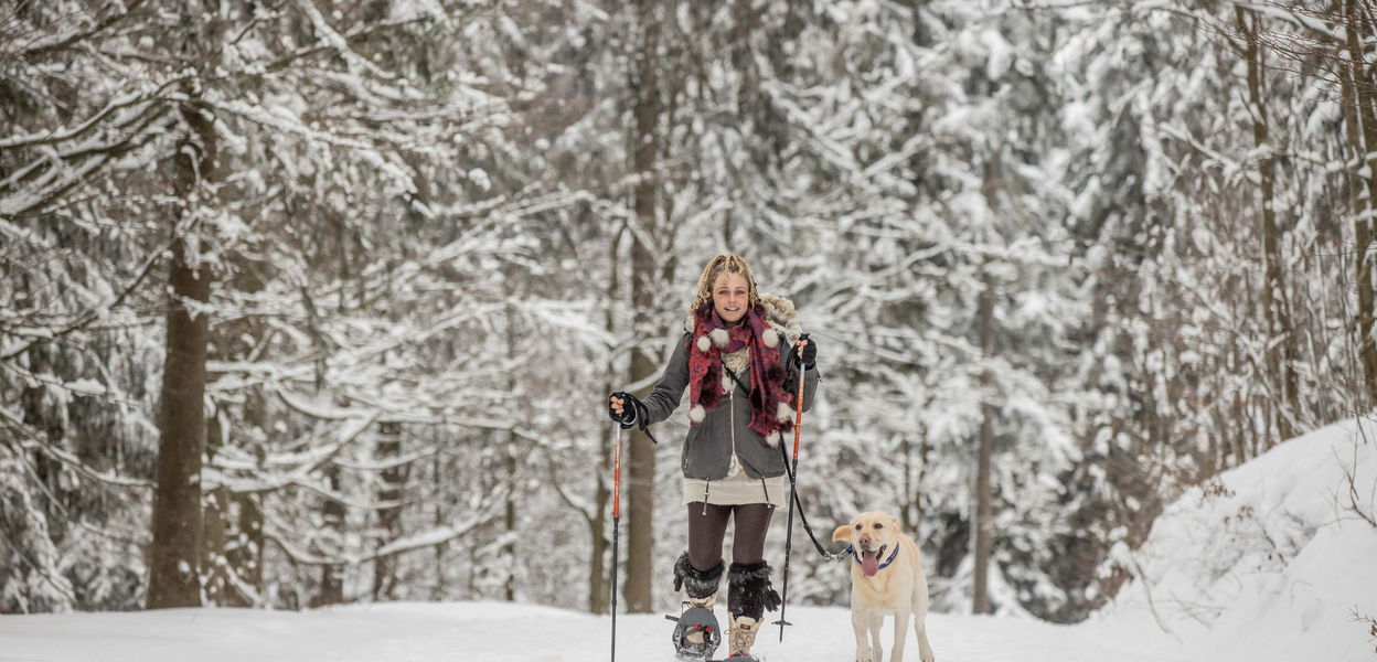 Dame beim Schneeschuhwandern mit Hund